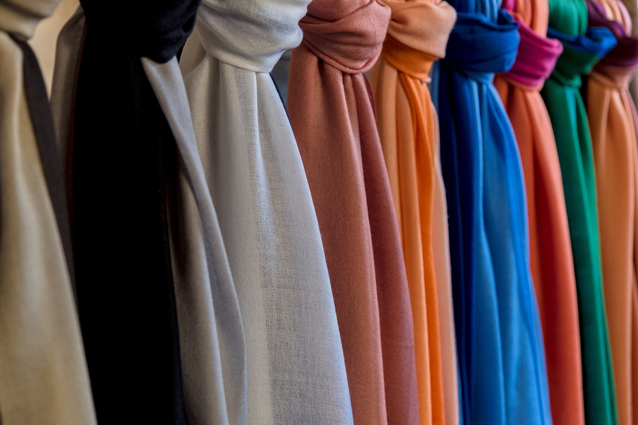 colorful scarves lined up along a wall. Image by Nino Carè from Pixabay