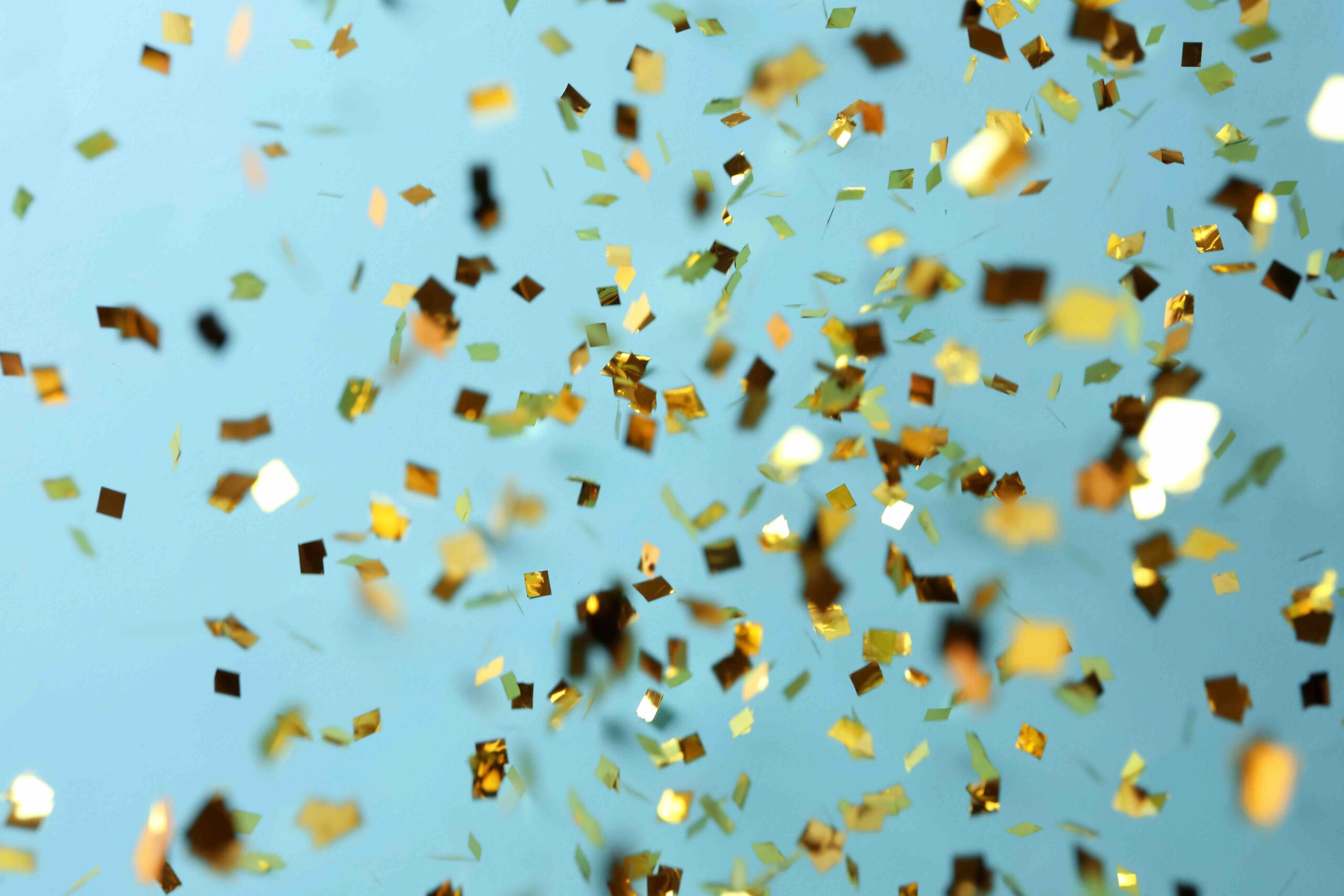 Shiny golden confetti falling down on light blue background