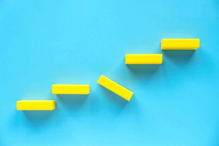 Yellow blocks along a wall with the block in the middle of kilter. Meant to show a stumbling block along the path to success.