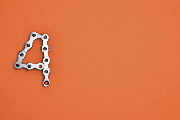Soft orange background with a silver 4 made out of a bicycle chain.