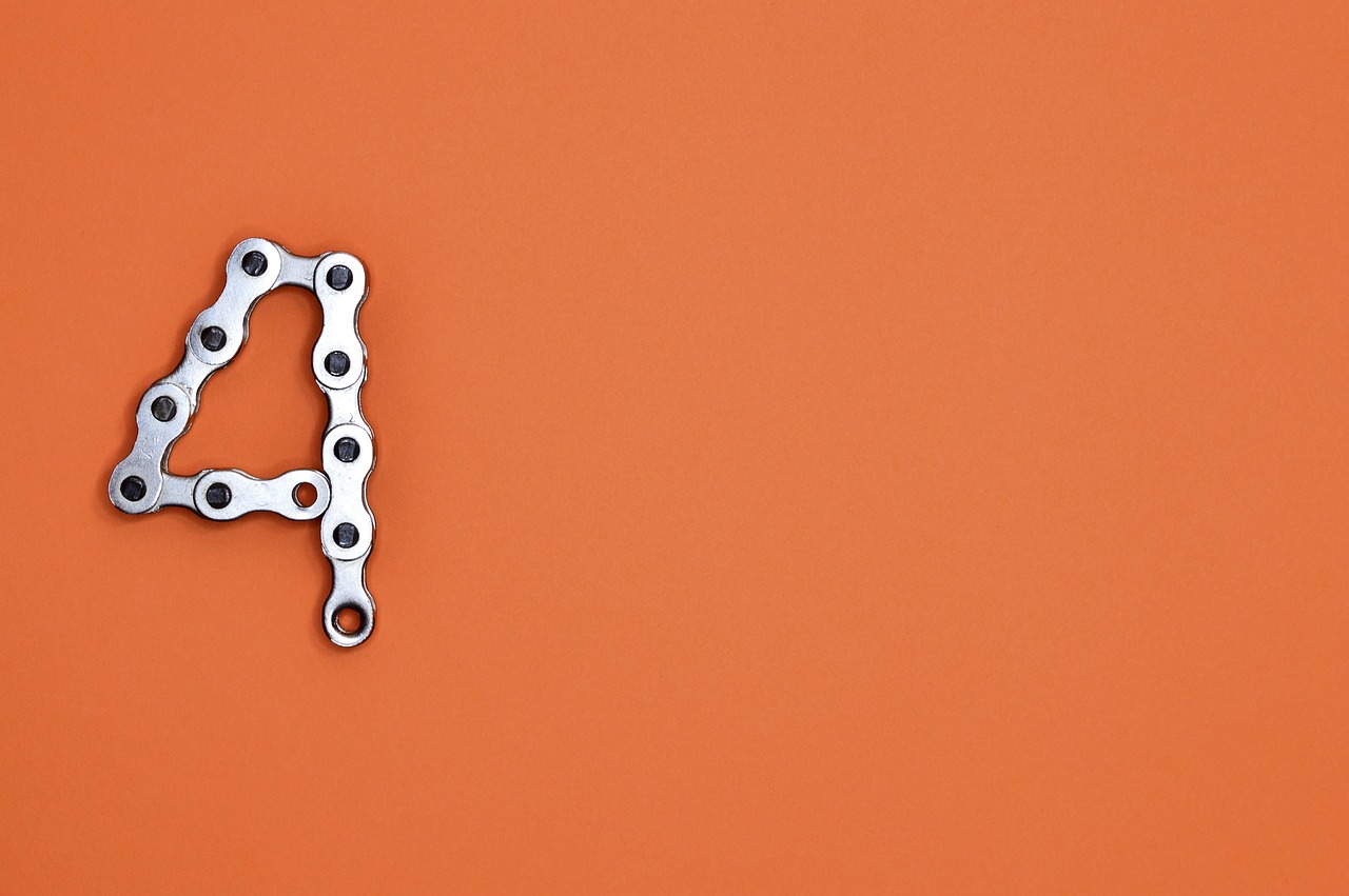 Soft orange background with a silver 4 made out of a bicycle chain.
