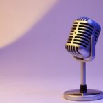 photo of a silver microphone with a lilac purple background.