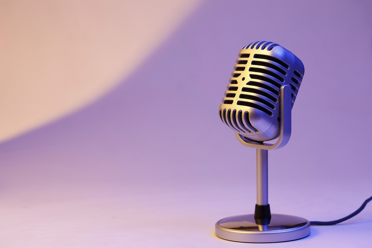 photo of a silver microphone with a lilac purple background.